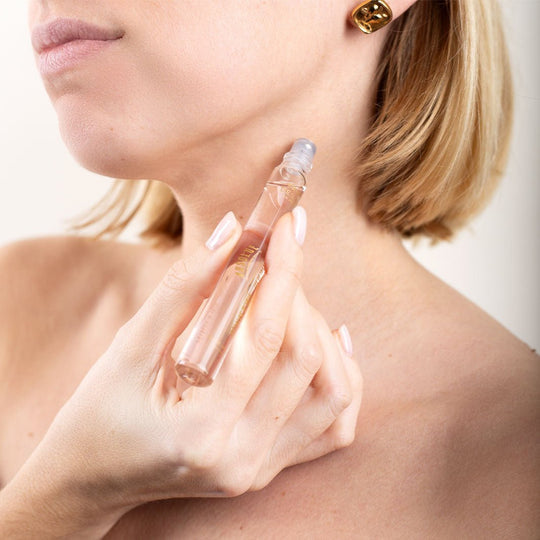 A woman applying the roll-on perfume to her neck