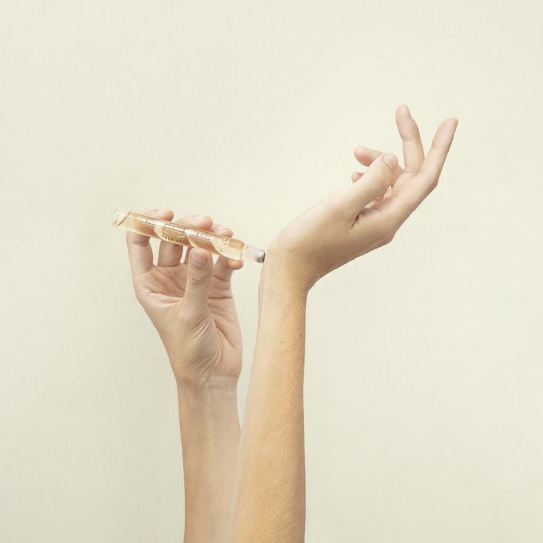 two hands using the rollerball perfume on their wrist
