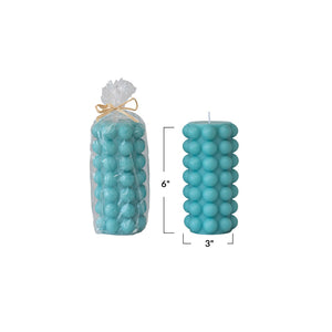 Unscented Hobnail Pillar Candle 6"H in Cyan Blue shown in cellophane packaging and without packaging. Measurements of height and width are shown in photo